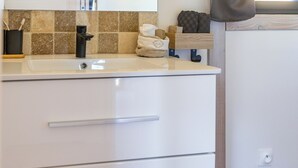 A bathroom with a white sink, mirror, and wooden floor. - Wellness retreat with a hot tub and fitness center overlooking the lake (Vaivre-et-Montoille)