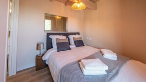A bedroom with a bed, a bedside lamp, a mirror, and a window. - Wellness retreat with a hot tub and fitness center overlooking the lake (Vaivre-et-Montoille)