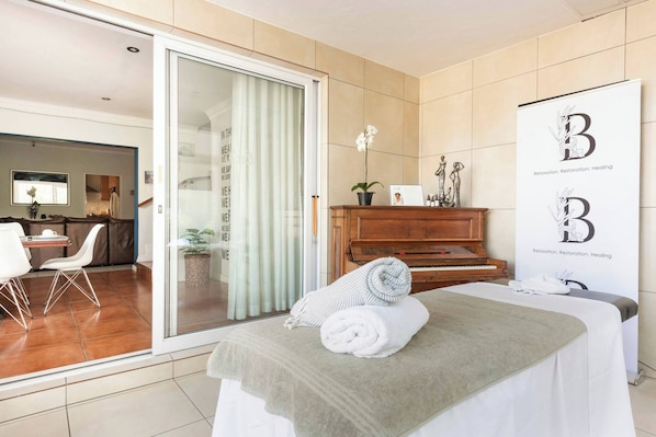 Una habitación de hotel con una cama, un piano, un ventanal corredero a un balcón y un cartel con el logotipo del hotel.