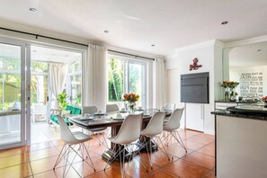 A modern kitchen with a dining area, large windows, and a view of the outdoors. - Lu's Guest House your homely experience (Paarl)