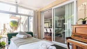 Un dormitorio con cama, un piano y un ventanal corredizo que da a un balcón.