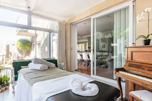 A bedroom with a bed, a piano, and a sliding glass door leading to a balcony. - Lu's Guest House your homely experience (Paarl)