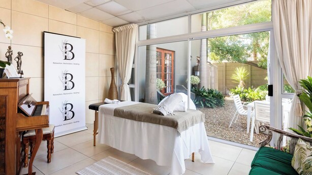 Un cuarto de spa con una camilla de masaje, un piano y un cartel con las letras 'B' y las palabras 'Relajación, Restauración, Curación'.