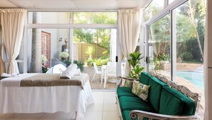 Una habitación con cama, sofá verde y vistas a una piscina y jardín.