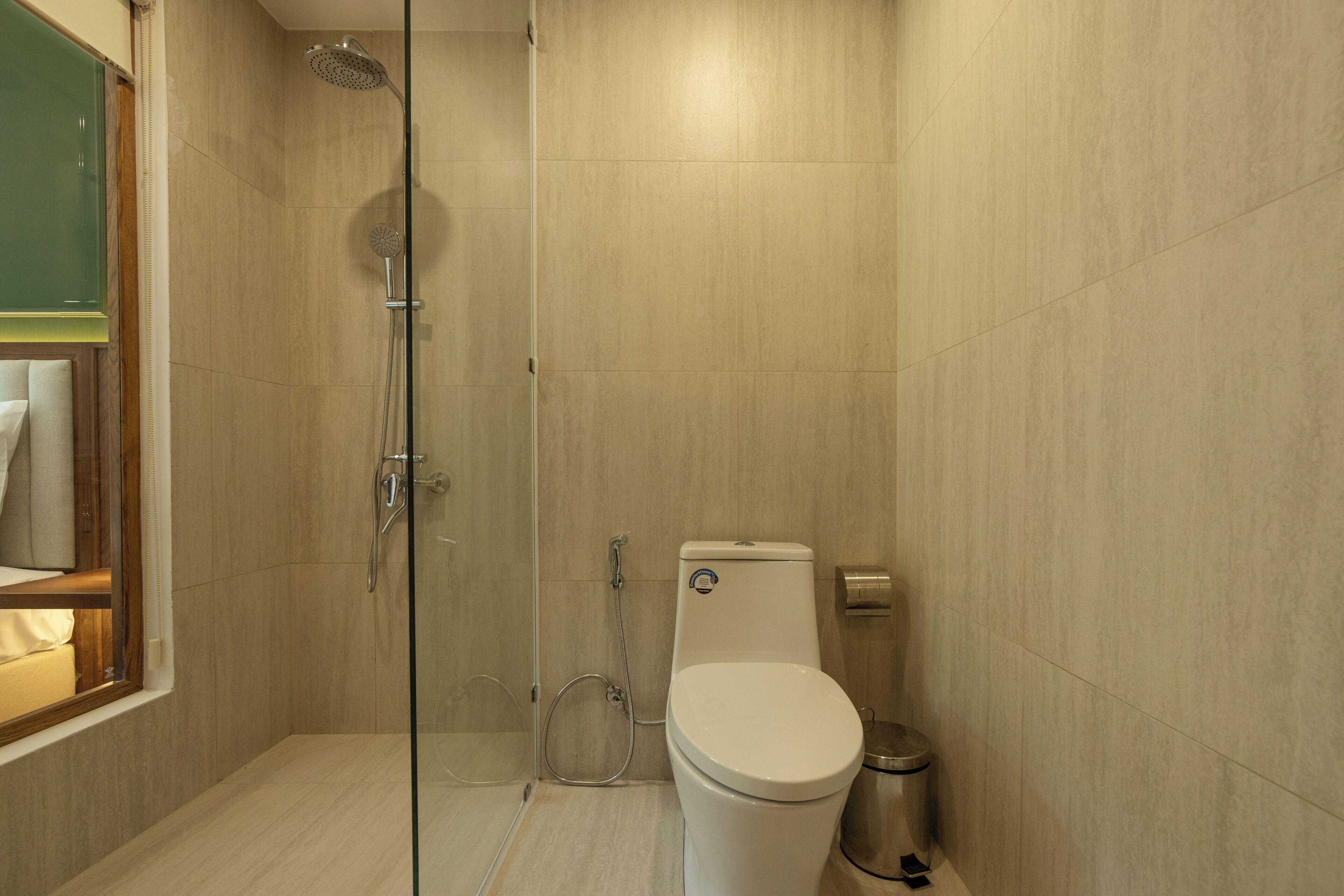 Une salle de bain moderne avec une douche à parois de verre, des toilettes et une poubelle.