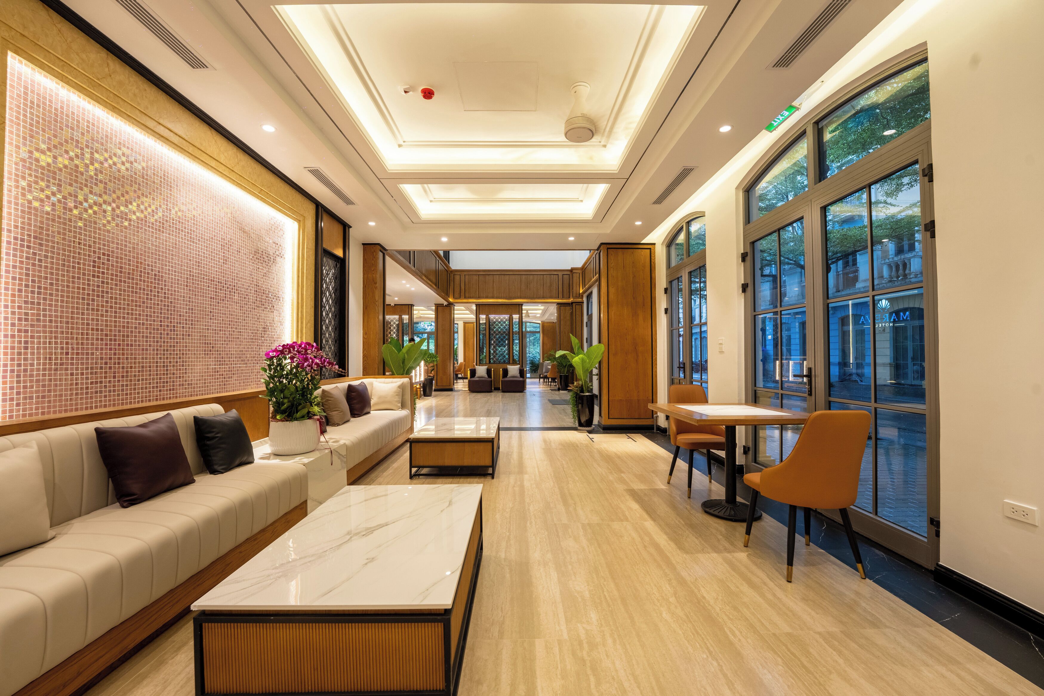 Un hall de hotel con zona de estar, mostrador de recepción y grandes ventanales.