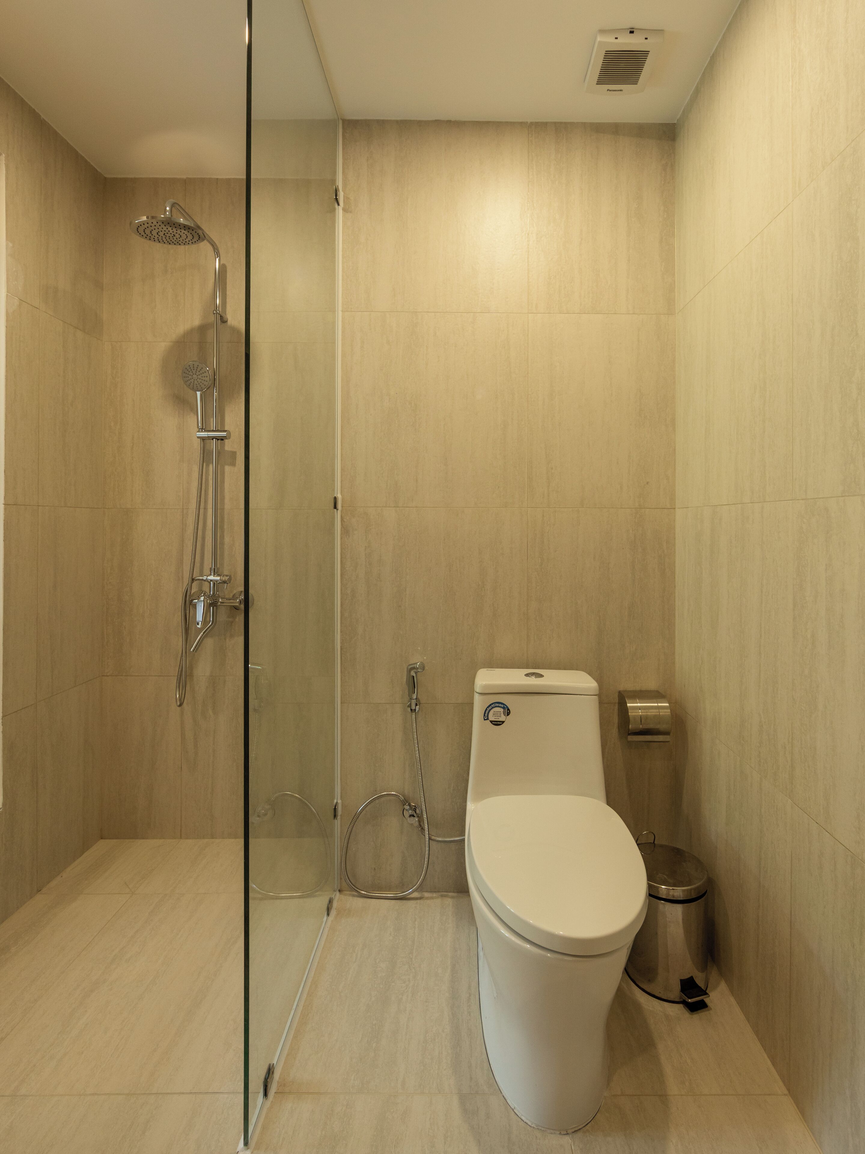Un baño moderno con ducha de vidrio, inodoro y cubo de basura.