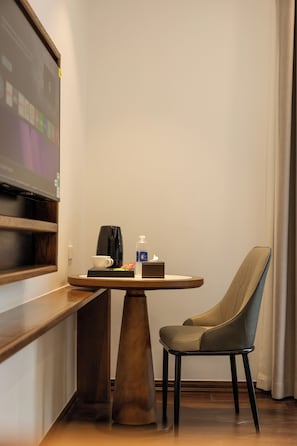 A hotel room with a wooden desk, a chair, a coffee maker, a cup, a bottle of hand sanitizer, and a screen displaying a presentation. - MAREVA KHEM BEACH HOTEL Free Beach Buggy (Phu Quoc)