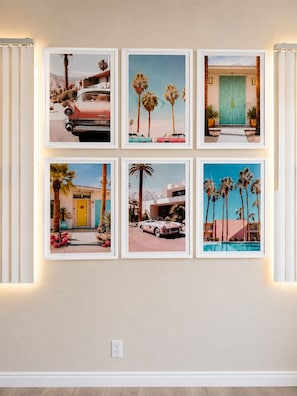 Eine Wand mit sechs gerahmten Bildern, die Oldtimer, Palmen und einen Hauseingang zeigen.