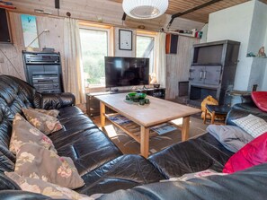 A cozy living room with a leather sofa, a wooden coffee table, a television, and a fireplace. - 10 Person Holiday Home in Harboore (Harboore)