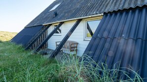A rustic building with a sloped roof, a wooden bench outside, and a corrugated metal wall. - 10 Person Holiday Home in Harboore (Harboore)