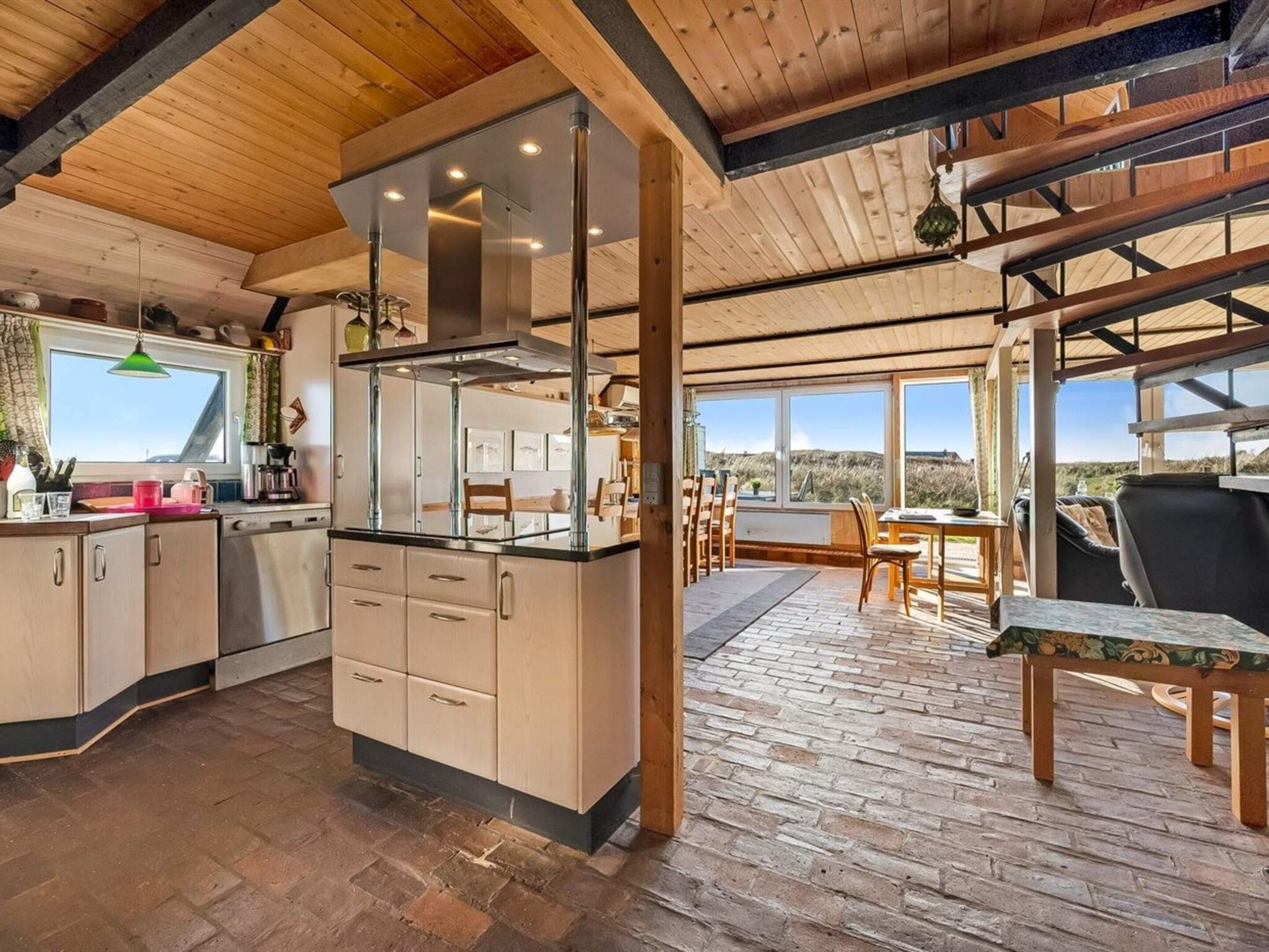 A modern kitchen with a central island, wooden beams, and large windows.
