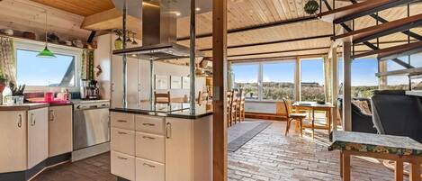 A modern kitchen with a central island, wooden beams, and large windows.