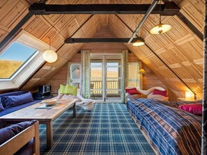 A cozy attic bedroom with a sloped ceiling, a large window, a bed, a sofa, and a table. - 10 Person Holiday Home in Harboore (Harboore)