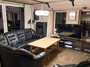 A living room with a black leather sofa, a wooden coffee table, a flat-screen TV, and a ceiling fan. - 10 Person Holiday Home in Harboore (Harboore)