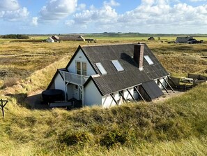 Una casa con techo inclinado, un balcón y una pequeña zona de estar al aire libre.