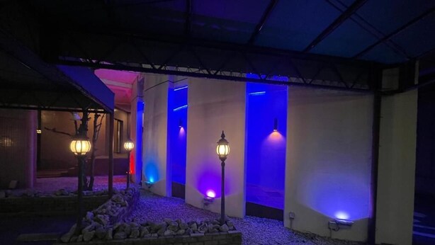 Área externa coberta com vasos de pedra e luminárias fixadas na parede.