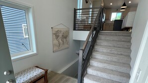 Una escalera con barandilla de madera, un banco con estampado floral y un mapa del mundo en la pared.