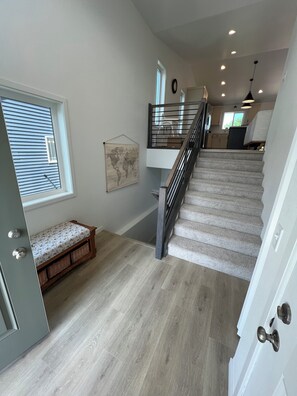 A staircase with a wooden handrail, a bench with a floral pattern, and a world map on the wall. - 4BR 2Bath Retreat Near Fargo Dome, MSUM, NDSU & Fargo Downtown (Moorhead)