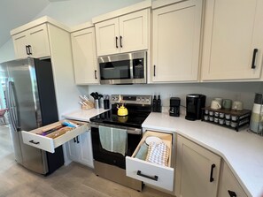 A modern kitchen with stainless steel appliances, white cabinetry, and a countertop with various kitchen items. - 4BR 2Bath Retreat Near Fargo Dome, MSUM, NDSU & Fargo Downtown (Moorhead)