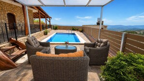 A rooftop pool area with wicker furniture and a stone wall.