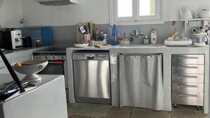A modern kitchen with a dishwasher, stove, and a window above the sink. - A quiet Cycladic-style family home with a pool and an exceptional ocean view. (SIFNOS)
