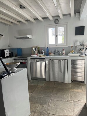 A modern kitchen with a dishwasher, stove, and a window above the sink. - A quiet Cycladic-style family home with a pool and an exceptional ocean view. (SIFNOS)
