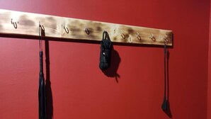 Een houten rek met haken tegen een rode muur.