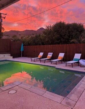 A swimming pool with lounge chairs and a wooden fence. - Modern Desert Retreat. Pool & Spa . 3 King Suites. Quiet Upper Cove Location (Cathedral City)