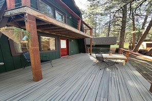A wooden deck with a red door, a small table, and chairs. - Unplug & Unwind - Cozy Alpine A-Frame Tucked Away in the Arizona Pines (Flagstaff)