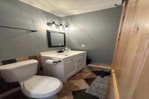 A bathroom with a toilet, sink, mirror, and light fixture. - Unplug & Unwind - Cozy Alpine A-Frame Tucked Away in the Arizona Pines (Flagstaff)