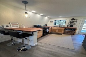 Eine moderne Küche mit einer Holztischinsel, Barhocker, integriertem Backofen und Mikrowelle.
