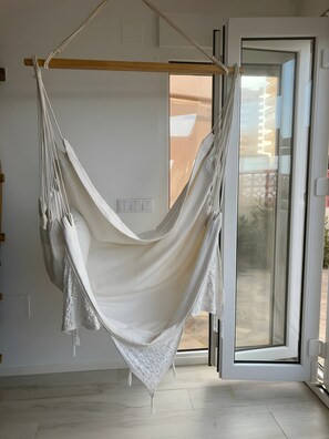 Eine Hängematte, die an einem Holzbalken befestigt ist, in einem Zimmer mit einer Schiebeglasdoor zur Außenfläche.