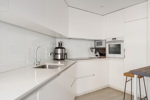 Eine moderne Küche mit weißen Schränken, Edelstahlgeräten und einem Holztisch.