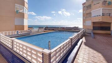 A swimming pool with a tiled deck and a view of the sea.