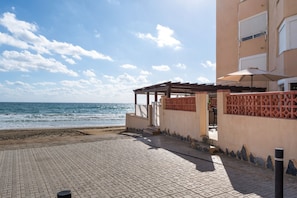 Ein Objekt direkt am Strand mit überdachter Terrasse, Meerblick und einem Gebäude mit strukturiertem Fassadendekor.