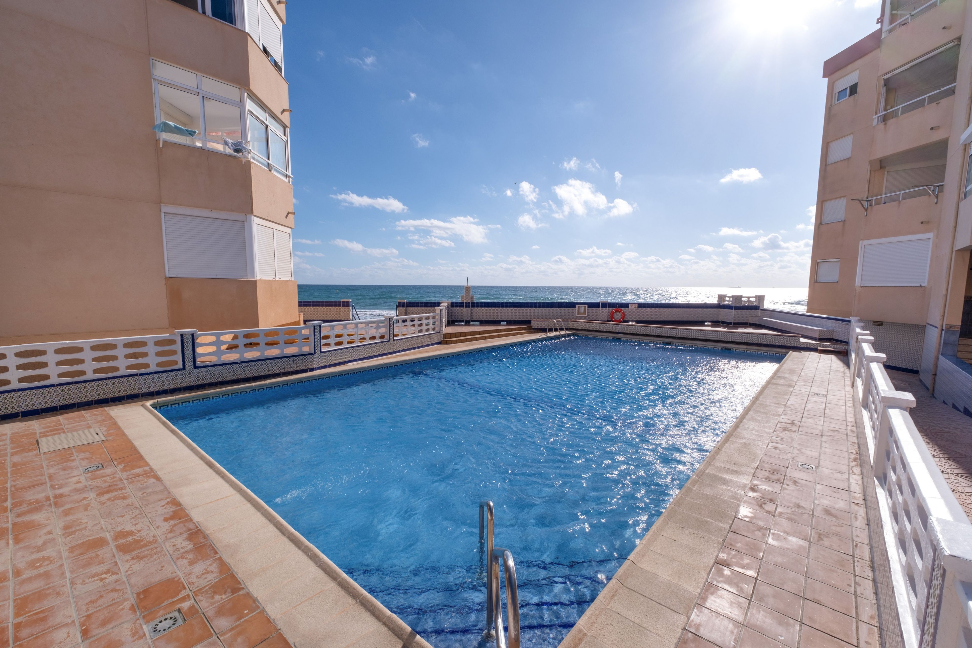 Una piscina con vista al mar, rodeada de edificios.