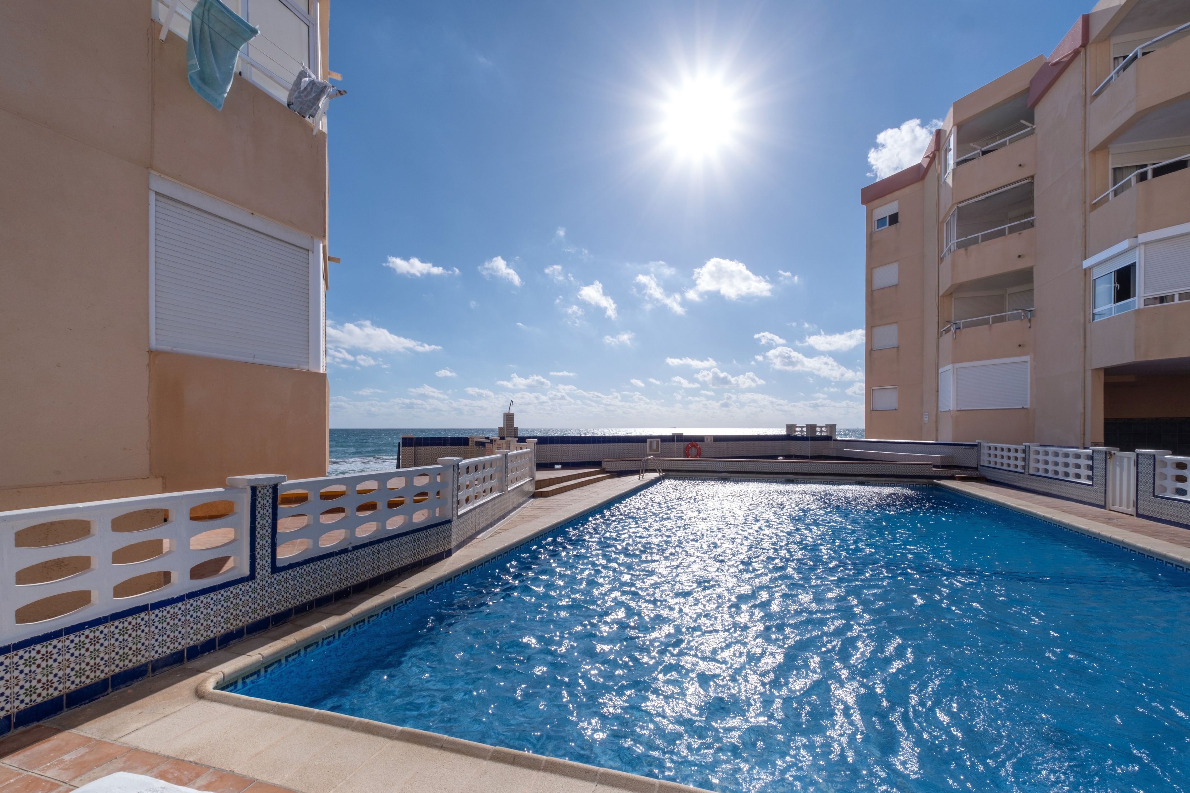 Ein Pool mit Blick auf das Meer, umgeben von Gebäuden mit Balkonen.