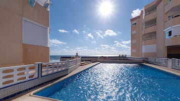 Ein Pool mit Blick auf das Meer, umgeben von Gebäuden mit Balkonen.