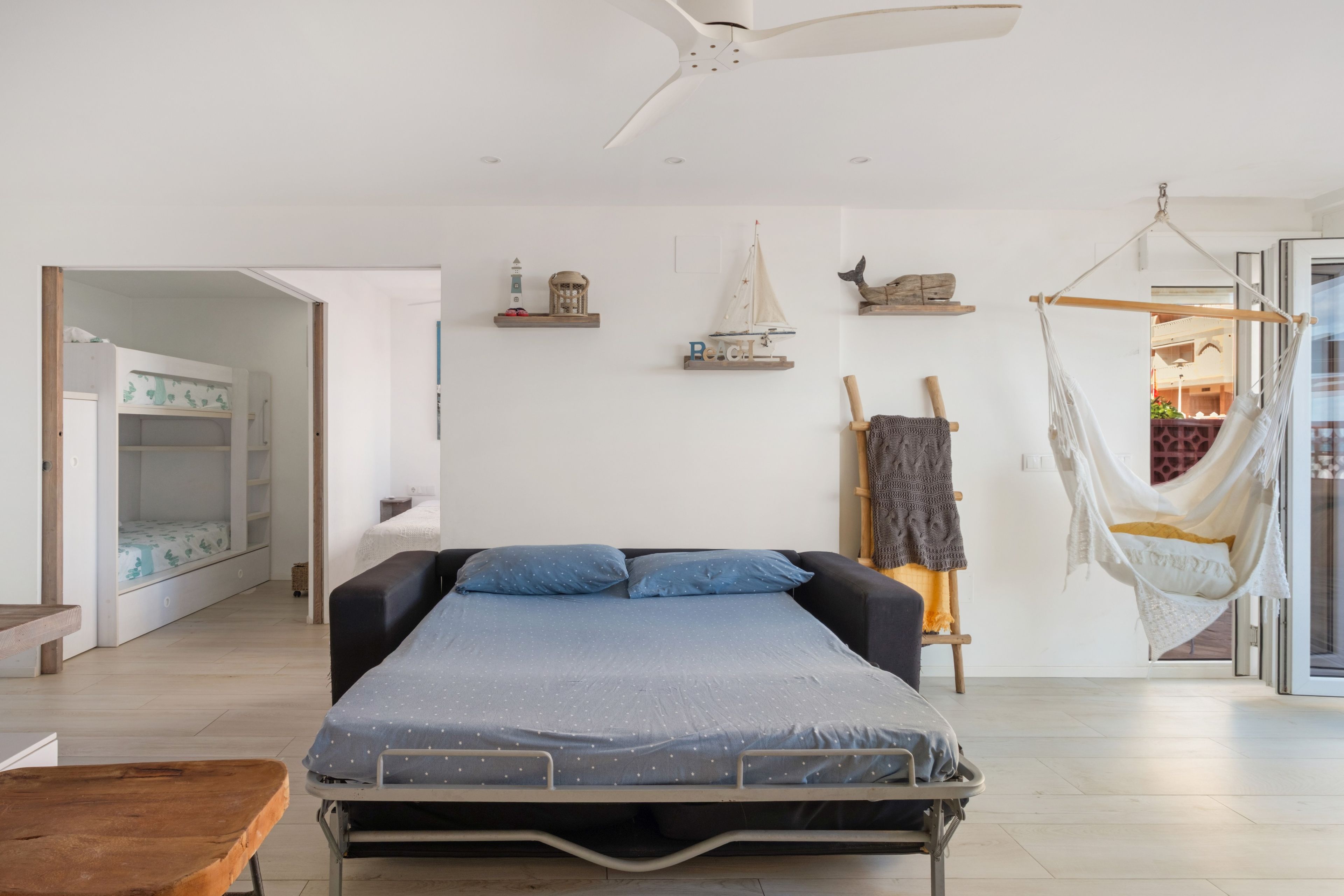 Een slaapkamer met een bed, een hangmat en een plank met decoratieve spullen.