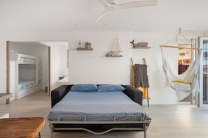 Ein Schlafzimmer mit einem Bett, einer Hängematte und einem Regal mit Dekoration.