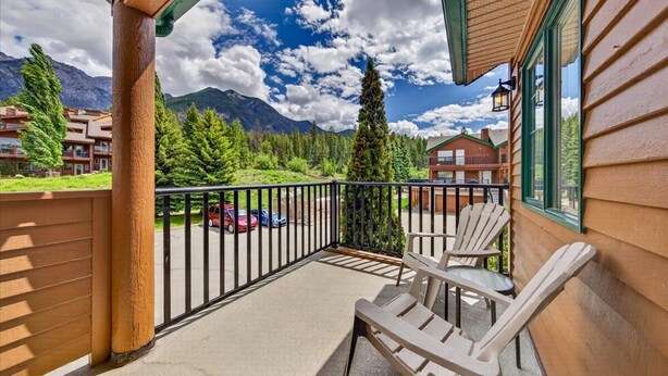 Un balcone con sedie, vista sulle montagne e un'area di parcheggio.