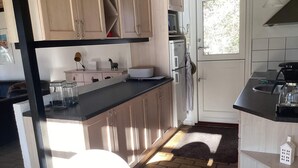 Une cuisine avec des meubles en bois, un plan de travail noir et une fenêtre.
