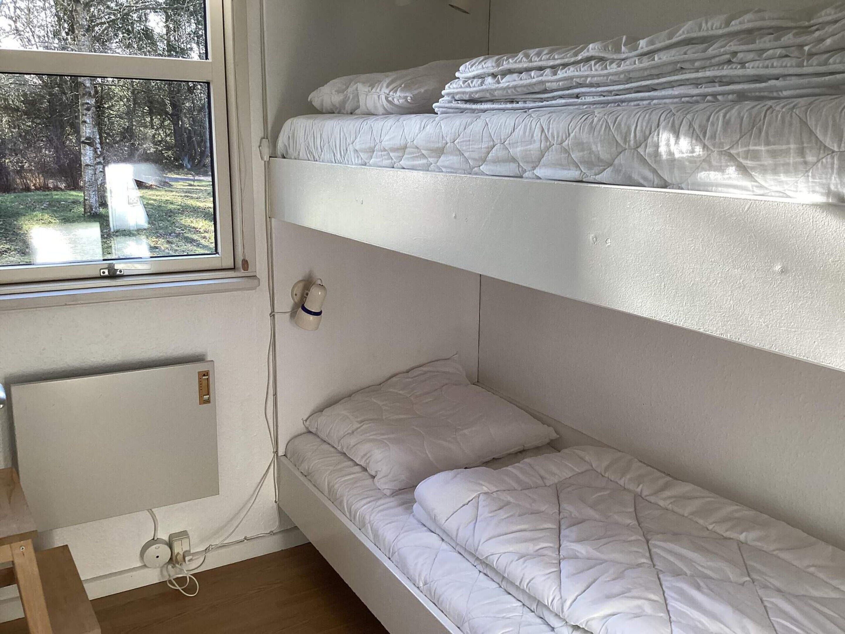 A bunk bed room with a window, a wall socket, and a power outlet.