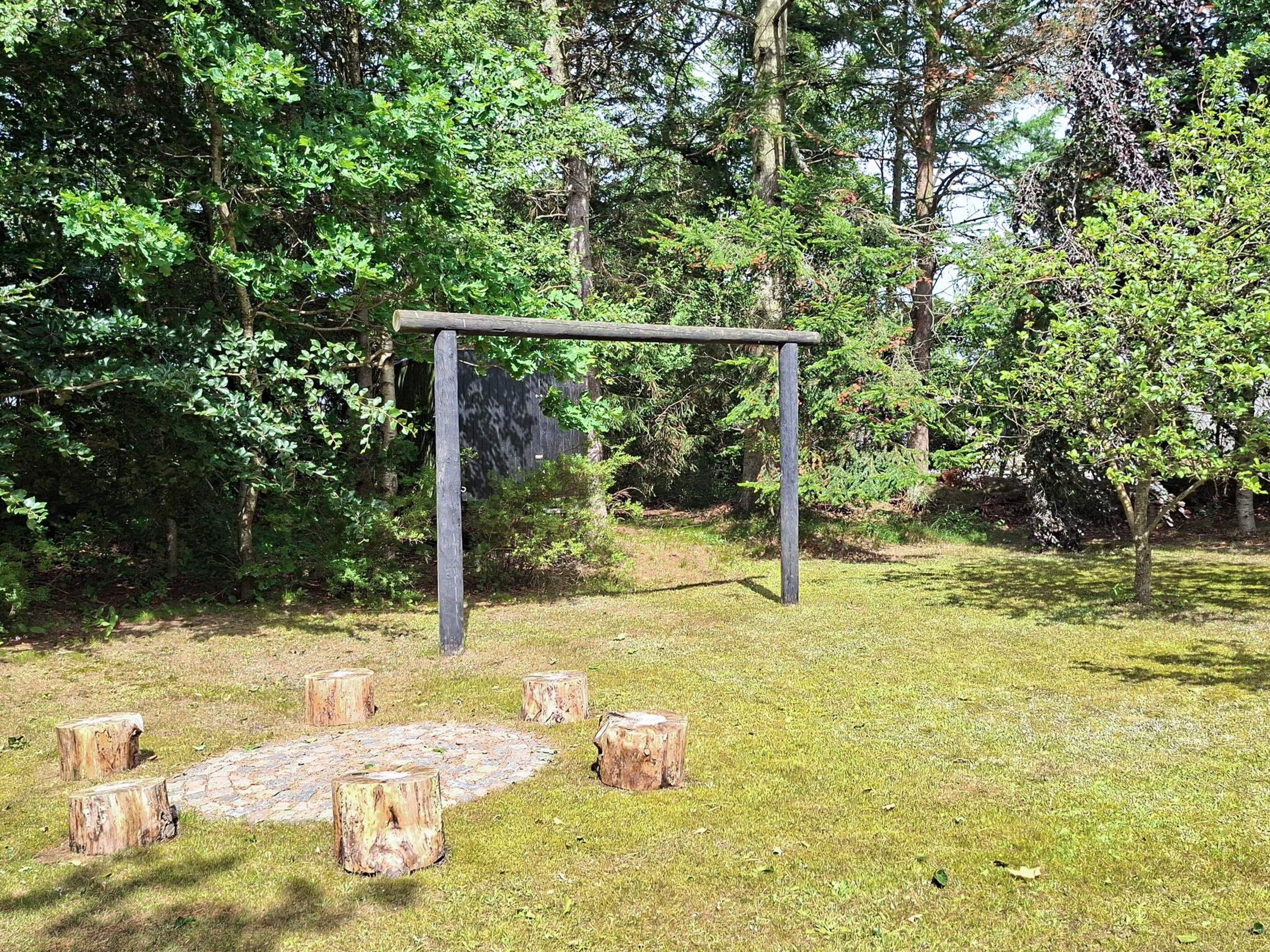 An outdoor wooden structure with a circular seating area surrounded by tree stumps.