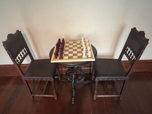 A chessboard on a table with two chairs. - In addition to their room, our guests can enjoy a garden, a terrace, a veranda, and a lounge (Chevanceaux)