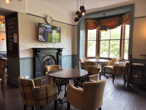 A dining area with a fireplace, television, and plaid chairs.