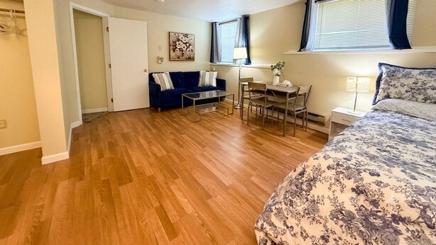 Een slaapkamer met een bed, een bureau, een stoel, een bank en een raam met gordijnen.