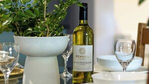 A dining table with a white bowl, a bottle of wine, and a potted plant. - Scandi Garden Apartment (Stellenbosch)