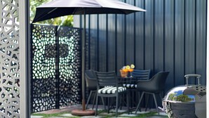 An outdoor patio with a grill, chairs, and a table with fruit. - Scandi Garden Apartment (Stellenbosch)
